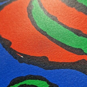 May include: Close-up of a colorful abstract design with bold shapes and colors. The image features a combination of red, green, blue, and yellow hues, outlined in black. The design has a textured appearance.