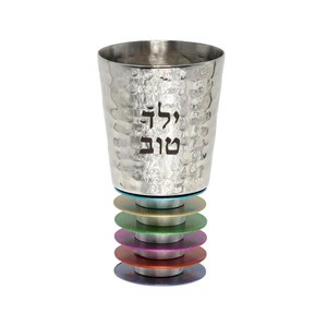 Puede incluir: Una copa de Kiddush de plata con un acabado martillado y las palabras hebreas "L'chaim" y "Shalom" grabadas en el lateral. La copa está sentada sobre una pila de anillos coloridos.