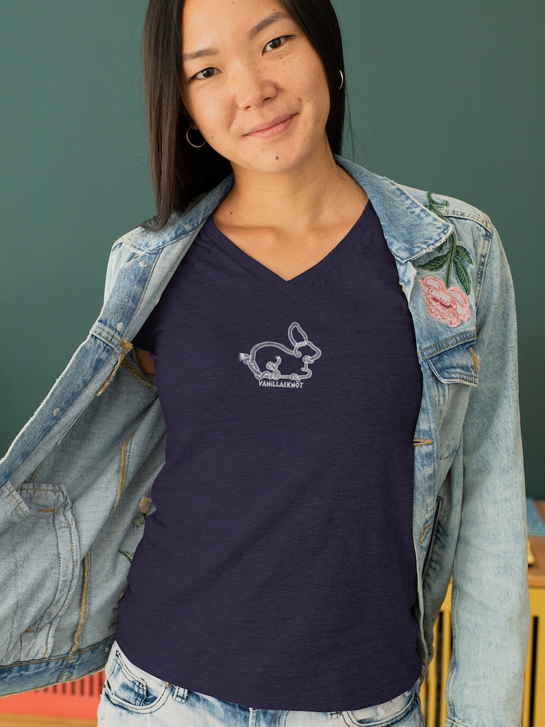 Peut inclure: Un t-shirt bleu marine &agrave; col en V avec un contour blanc d'un lapin et le texte "VanillaKnot" sur le devant.