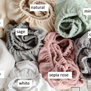 It shows fitted crib sheets made of organic muslin cotton. Perfect for baby oval or bedside cribs, bassinets and cradle. It's cozy pastel baby nursery, ideal for all Stokke cribs.