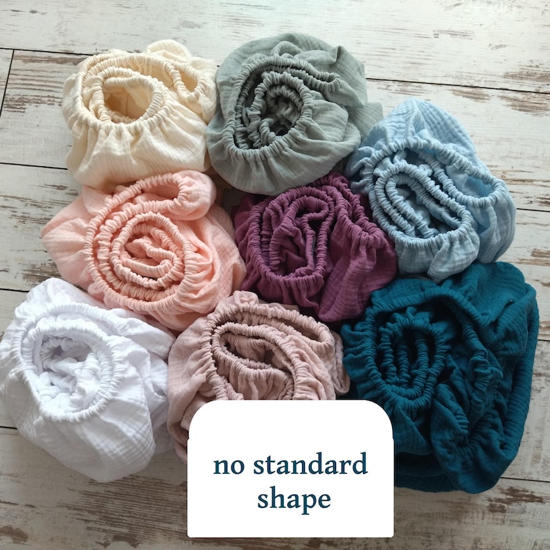 May include: A collection of eight circular fabric covers with elasticized edges in various colors including white, cream, light pink, dusty rose, sage green, light blue, dark purple, and teal, featuring the text no standard shape.