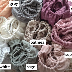 It shows fitted crib sheets made of organic muslin cotton. Perfect for baby oval or bedside cribs, bassinets and cradle. It's cozy pastel baby nursery, ideal for all Stokke cribs.