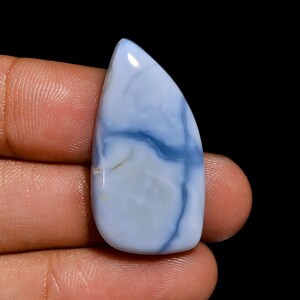 May include: A light blue cabochon opal gemstone with white and blue veins. The opal is a teardrop shape and has a smooth, polished surface.