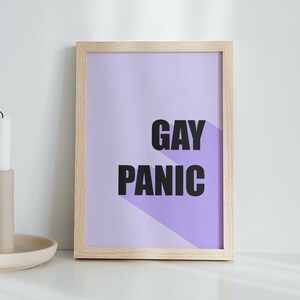 Puede incluir: Una impresión enmarcada con un fondo morado claro y el texto "GAY PANIC" en letras negras.