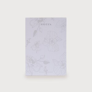 以下が含まれることがあります： 花柄のデザインが施された白いノート。表紙には「NOTES」と印刷されています。
