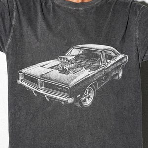 May include: Dark gray t-shirt featuring a detailed black and white illustration of a classic muscle car, a Dodge Charger. The car graphic includes the text "Charger 69". The shirt also has the text "Visual Sensei" at the bottom.