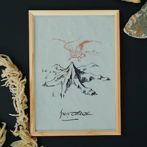 May include: A framed print of a black and white illustration of a mountain with a red dragon flying above it. The print is on a light grey background and has the text "for collection" written in black ink at the bottom.