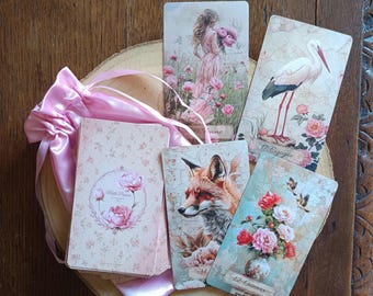 May include: A deck of oracle cards featuring vintage-style illustrations of a woman, a stork, a fox, and a floral vase, accompanied by a pink satin drawstring pouch. The cards display text including 29 Femme, 17 Cigogne, 14, and 12 Oiseaux.