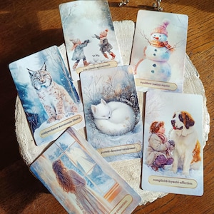 Peut inclure: Un ensemble de cartes de tarot avec des illustrations sur le thème de l'hiver. Les cartes représentent un lynx, des enfants jouant, un bonhomme de neige, un renard endormi, une femme et un enfant avec un chien. Chaque carte a une phrase en français.