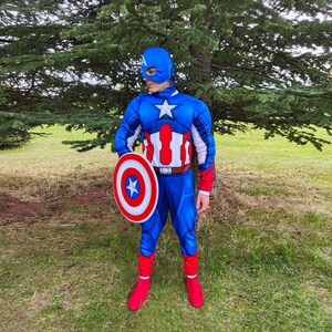 May include: A blue Captain America costume with a white star on the chest and a matching shield. The costume includes a blue mask, gloves, and boots. The shield is red, white, and blue with a star in the centre.