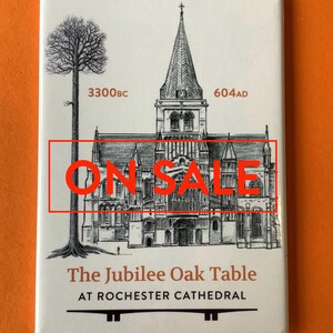 May include: A white magnet with a black and white illustration of Rochester Cathedral and a large oak tree. The text "ON SALE" is in red letters. The text "The Jubilee Oak Table at Rochester Cathedral" is below the illustration.