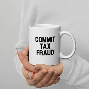 Puede incluir: Taza de cerámica blanca con texto negro que dice "COMMIT TAX FRAUD".