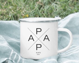 May include: White enamel mug with a silver rim and a large handle. The mug features the word "PAP" in a stylized design, with the name "ALAIN" and the year "2025" printed below. The mug is sitting on a blue and white striped blanket.