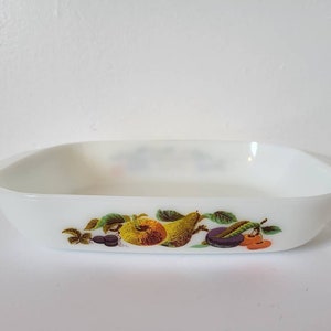 Peut inclure: Plat à four rectangulaire blanc avec un motif de fruits. Le motif représente une poire, une pomme et des cerises avec des feuilles vertes.