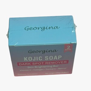 May include: A blue and pink box with the text "Georgina Kojic Soap Dark Spot Remover" and "Skin Brightening Bar" on the front. The box also lists the ingredients: Vitamin C, Collagen, Turmeric, and Retinol. The box contains two bars of soap.