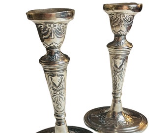 May include: A pair of silver candle holders with intricate floral designs. The holders have a classic, elegant style.