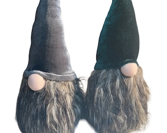 May include: Two decorative gnomes with long, pointed hats and shaggy beards. One gnome has a grey hat and the other has a dark green hat. Both gnomes have a round, light-coloured nose and a fluffy, brown and grey beard.