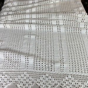 Peut inclure: Jeté en crochet blanc avec un bord festonné. La couverture a un design délicat et ajouré.