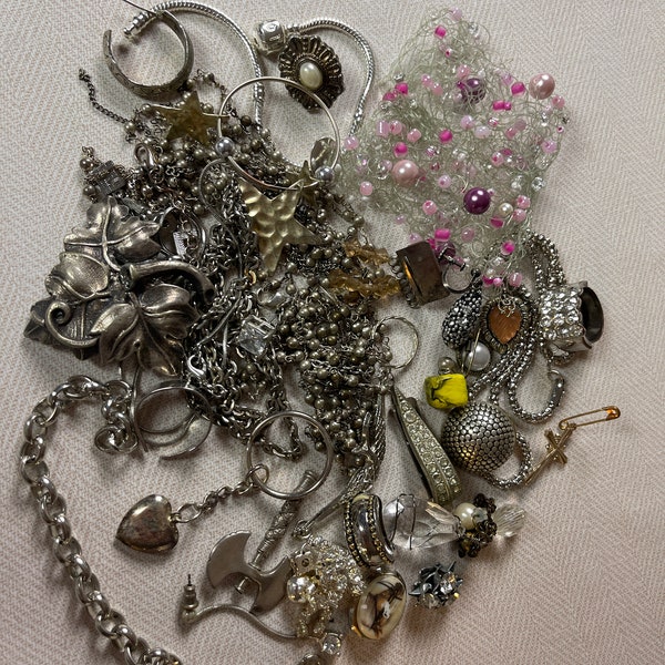 This is a 1/2 pound lot of broken and not, vintage and newer craft jewelry. The majority of these are wearable or for craft Silver tones