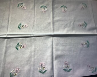 May include: White linen tablecloth with embroidered pink and green floral designs. The tablecloth is folded in half, showing the pattern on both sides.