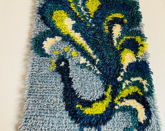May include: A blue, green, and yellow abstract rug with a peacock design. The rug is made of yarn and has a fuzzy texture.