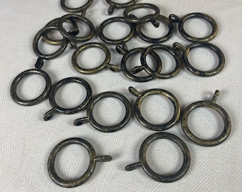 May include: A pile of 18 antique gold curtain rings. The rings are made of metal and have a smooth, slightly textured finish.