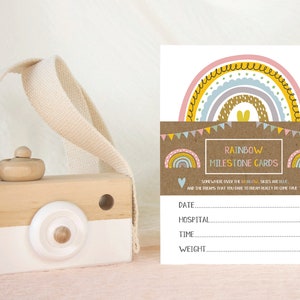May include: Rainbow milestone cards featuring a colourful rainbow design and the text "Somewhere over the rainbow, skies are blue and the dreams that you dare to dream really do come true". The cards have spaces to record the date, hospital, time, and weight.