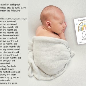 May include: A baby boy sleeping on a white blanket. A rainbow-themed baby milestone card with the text "Today I am One week old" is on the right side of the image. The card has a space for a date.