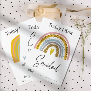 May include: A set of baby milestone cards featuring a rainbow design. Each card has a different milestone, such as "Today I first smiled". The cards are printed on white cardstock and have a simple, modern design.
