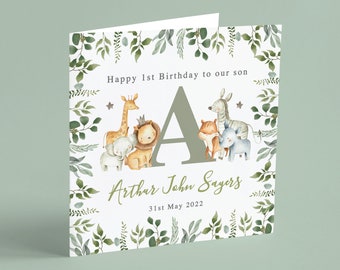 May include: A white card with a green leafy border. The card says "Happy 1st Birthday to our son Arthur John Sayers 31st May 2022". There is a large green letter A in the center of the card with a giraffe, lion, elephant, fox, zebra, and rhino surrounding it.