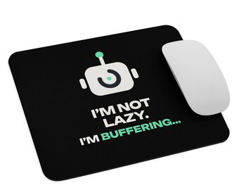 May include: A rectangular black mouse pad featuring a white robot icon with a teal accent. Below the icon, the white text reads I'M NOT LAZY. The word BUFFERING... is printed in teal below it. A white computer mouse rests on the pad.