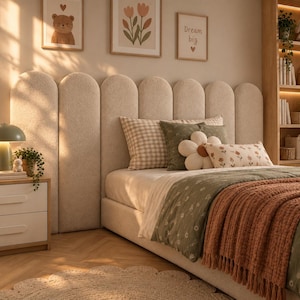 May include: A beige upholstered headboard with a series of vertical, rounded-top panels. The bed is dressed in a green floral patterned quilt, a rust-coloured fringed throw blanket, a checkered pillow, and a white flower-shaped decorative pillow.