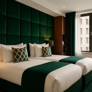 May include: A hotel bedroom with two single beds, white linen, and emerald green accents. The headboard is a padded, dark green wall. Cushions with a gold diamond pattern add a touch of elegance. A dark green rug and curtains complete the look.