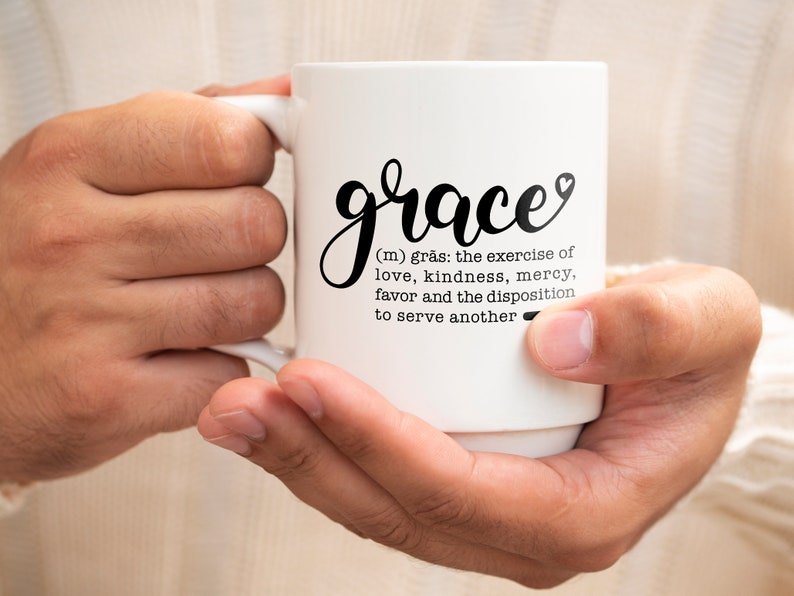 May include: White ceramic coffee mug with black text that reads "grace (m) gr&auml;s: the exercise of love, kindness, mercy, favor and the disposition to serve another".