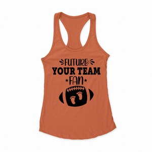 Puede incluir: Un top de tirantes naranja quemado con un gr&aacute;fico negro que dice "Future Your Team Fan" con un bal&oacute;n de f&uacute;tbol y dos huellas de pies dentro del bal&oacute;n.