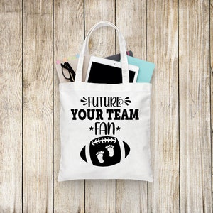 Puede incluir: Bolsa de lona blanca con texto negro que dice "Future Your Team Fan" y un gr&aacute;fico de f&uacute;tbol negro con dos huellas dentro.