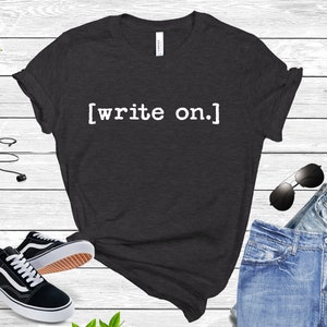 May include: A dark gray t-shirt with the text "[write on]" printed in white on the front.