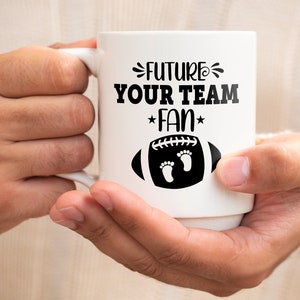 Puede incluir: Taza de cer&aacute;mica blanca con un dise&ntilde;o negro que dice "Future Your Team Fan" con un bal&oacute;n de f&uacute;tbol y huellas.