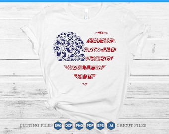 May include: White t-shirt with a red, white, and blue heart-shaped design. The heart is made up of floral patterns and resembles the American flag.