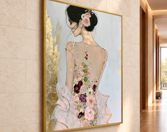 May include: A framed wall art print depicting a person seen from behind, wearing a dress adorned with floral patterns in shades of pink, burgundy, and white. The artwork features gold leaf accents and a light gray background.