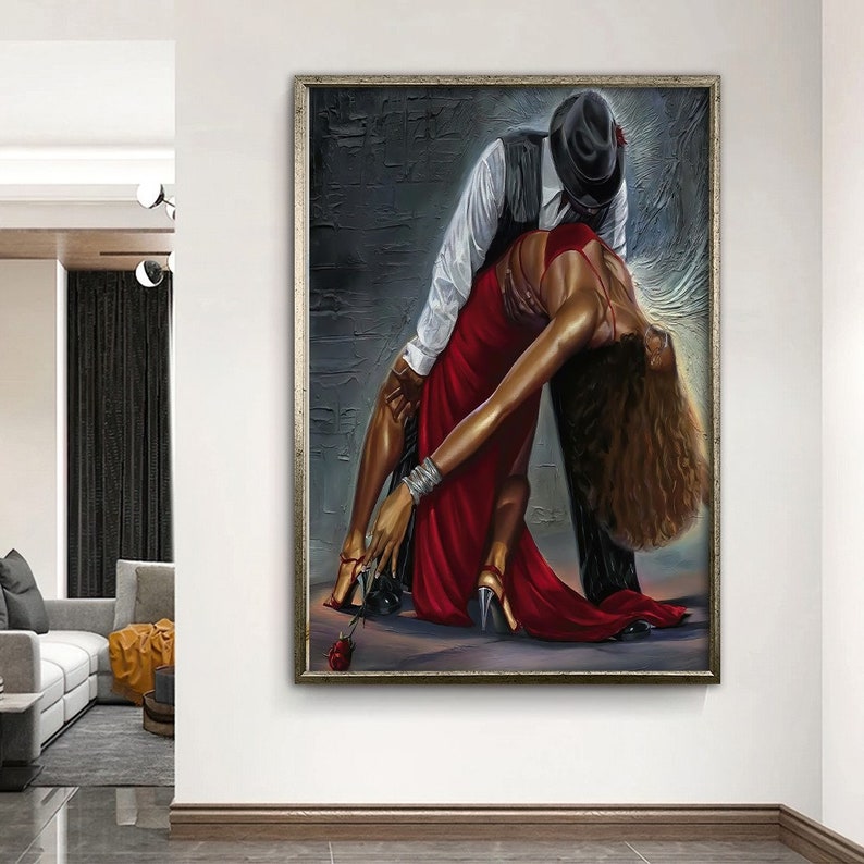 May include: A painting of a couple dancing. The woman is wearing a red dress and the man is wearing a black suit and a hat. The painting is set against a gray background.