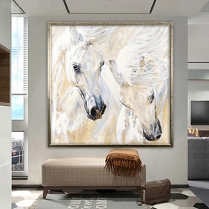 Op de afbeelding: Een schilderij van twee witte paarden met stromende manen, tegen een lichtbeige achtergrond. De paarden zijn in close-up afgebeeld, met hun hoofden en nekken prominent in de compositie.