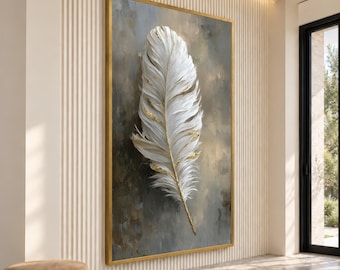 May include: A large rectangular wall art piece featuring a single white feather with gold leaf accents centered on a textured, muted gray and brown background. The artwork is enclosed in a thin, metallic gold frame, creating a focal point.