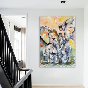 May include: A watercolor painting of three elephants. Two large elephants are standing side-by-side, with a smaller elephant standing in front of them. The elephants are painted in shades of gray, brown, and yellow, with a soft, watercolor background.