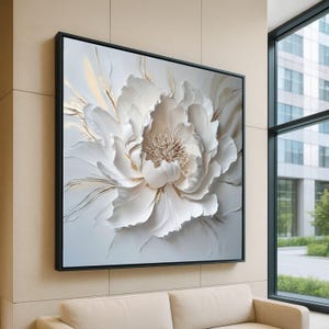 Può includere: Una grande opera d'arte murale quadrata incorniciata con una peonia bianca strutturata con dettagli dorati. L'opera è montata in una cornice nera su una parete di colore neutro. L'immagine è in un ambiente interno moderno.