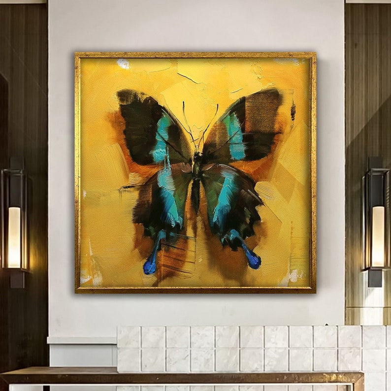May include: A painting of a blue and black butterfly with gold accents on a yellow background. The butterfly is framed in a gold frame.