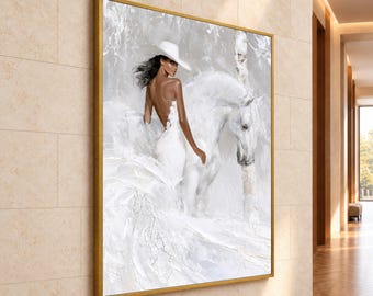 May include: A square wall art piece in a gold frame featuring a textured oil painting of a person wearing a white hat and dress standing beside a white horse in a snowy, abstract landscape with visible brushstrokes and white tones.