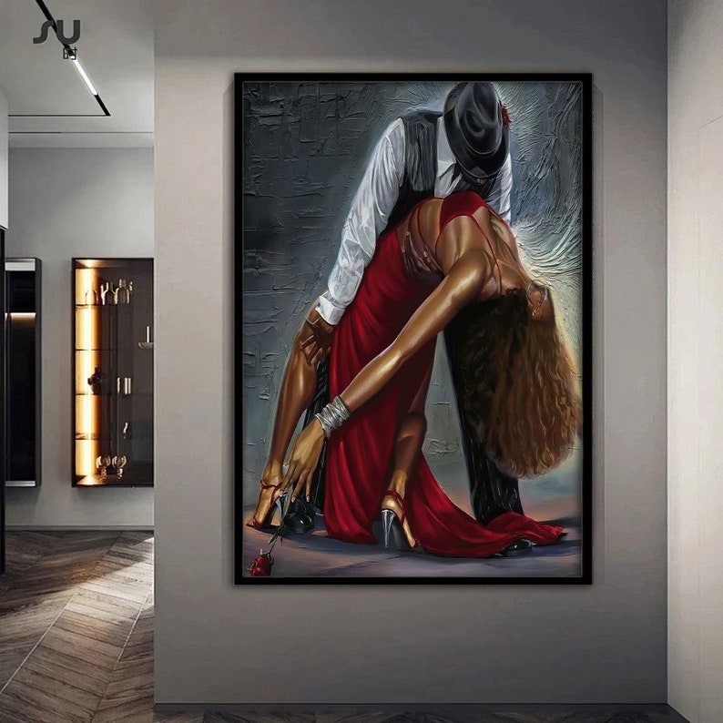 May include: A painting of a couple dancing. The woman is wearing a red dress and the man is wearing a black suit and a hat. The background is a textured gray wall.