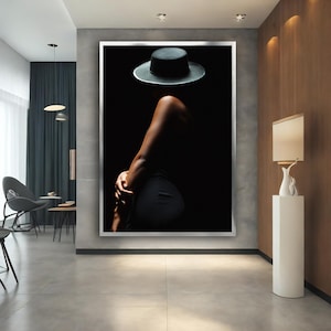 May include: A black and white photo of a person wearing a black hat and a black dress. The person is standing in a dark room and the light is coming from the left side of the image.