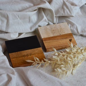 Puede incluir: Dos posavasos de madera con una parte superior de piedra en blanco y negro. Un posavasos tiene tres corazones grabados en la madera y el otro tiene un corazón grabado en la madera.